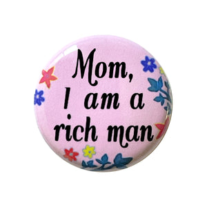 Mom, I Am A Rich Man 1" Pin-back Button or Magnet, Cher quote featured in Taylor Swift video, black cursive lettering on pink background with blue, yellow and red flowers and dark green leaves