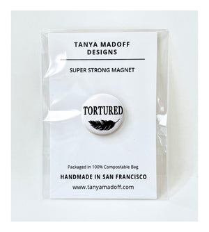 Tortured, 1" extra strength magnet, in honor of Taylor Swift's album, The Tortured Poets Department, black lettering and feather drawing on white background, packaged on recycled paper, in 100% compostable clear glassine bag